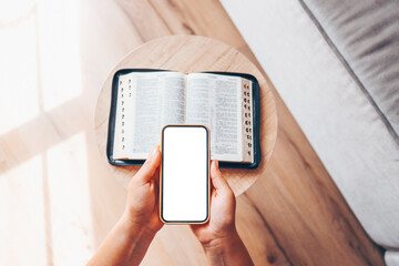 Woman hand hold and touch screen smart phone,cellphone in church over blurred bible holy and age book.