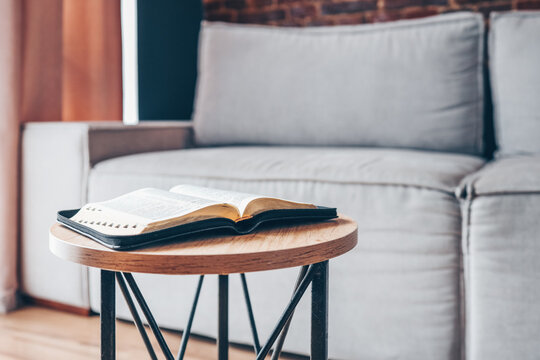 Open bible on table in living room, modern interior