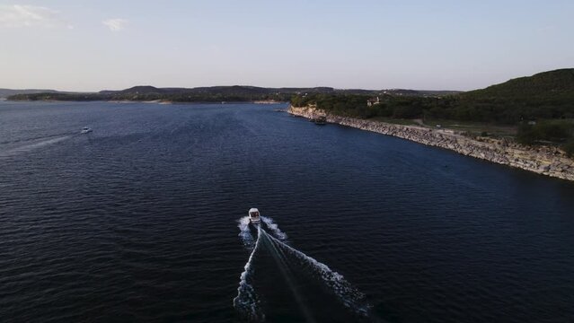 drone following boat during sunset on lake travis in Austin tx - windy point park cliff view