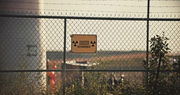 Nuclear Radiation Danger Sign on Barbed Wire Perimeter Fence with Contaminated Airborne Radioactive Particles in Exclusion Zone Slow Motion 4K