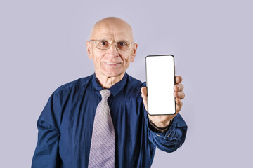 Elderly businessman wearing necktie and eyeglasses showing telephone with blank screen for mockup