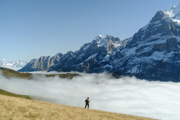 Fototapeta na wymiar Tourist stands in front of the mountains and clouds in the valley at Grindewald, Switzerland.