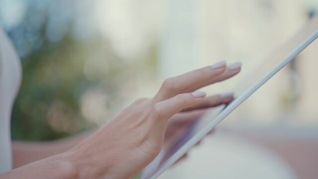 Close up video on female hands using a tablet, browsing and scrolling on a digital device