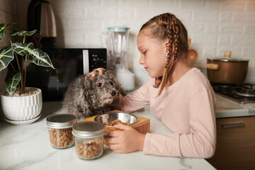 Girl enjoying spending time with her dog, she is feeding her with kibble