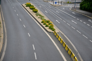 horizontal stripes for traffic signs. highway concrete barriers on the road. vehicle lane separator. yellow color with black stripes. flowerbed with blue perennials between the lanes of the highway