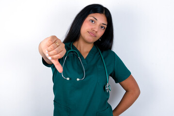 Doctor hispanic woman wearing surgeon uniform over white wall feeling angry, annoyed, disappointed...