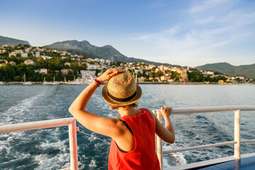 Rear view of a woman in a straw hat looking at the town from a boat