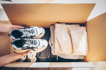 Volunteer with donations for poor people. Cardboard box with clothes for charity. Help poor. Woman...