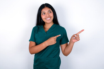 Doctor hispanic woman wearing surgeon uniform over white background smile excited directing fingers look empty space