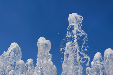 The gush of water of a fountain. Splash of water in the fountain on blue sky background