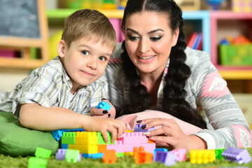 Fototapeta premium Young mother playing with cute little son