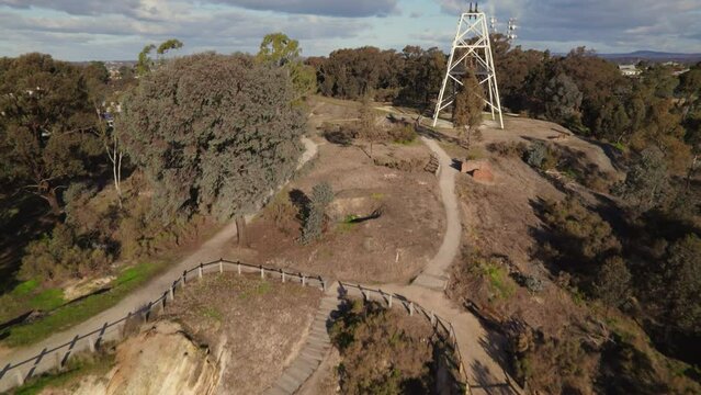 Sweeping drone shot of Victoria Hill Mining Reserve in Bendigo looking up to the poppet head on the hill
