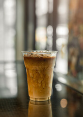 Ice coffee on a plastic cup with cream being poured into it showing the texture