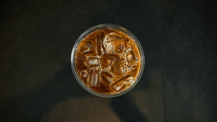Ice coffee on a plastic cup with cream being poured into it showing the texture