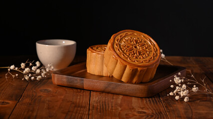 Traditional Chinese mooncakes with cup of tea and decorating with dried flower on wooden table