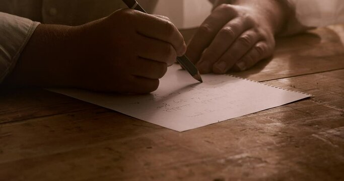 a man writes a letter on a paper on a table. Close up