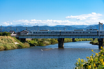 加賀平野を流れる動橋川を渡る北陸本線の特急列車