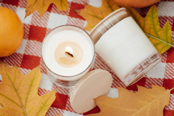 Close-up shot of burning candle and some yellow leaves around. Autumn mood, aromatic candles, calm atmosphere