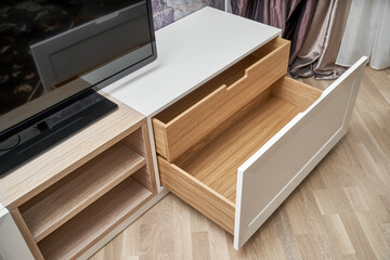 TV cabinet with open drawers in oak veneer and light enamel on wooden floor. Modern furniture with elegant design for room interior close view