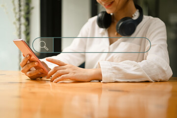 Smiling asian woman using smart phone with virtual screen of search bar button on foreground