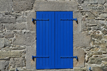 Blauer geschlossener Fensterladen an einem Steinhaus in der Normadie, Frankreich
