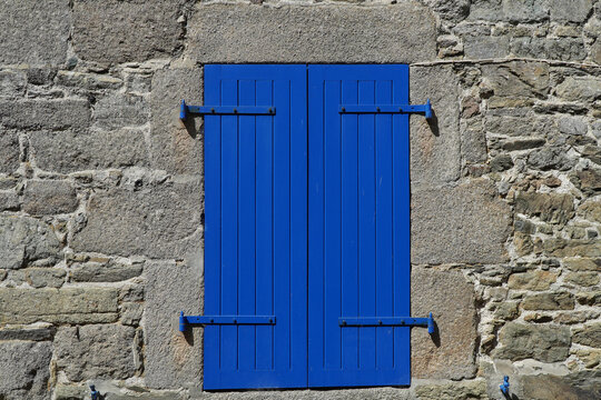 Blauer geschlossener Fensterladen an einem Steinhaus in der Normadie, Frankreich