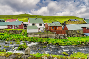Fototapeta na wymiar Colorful houses of Gjogv village and a small river flows into fjord. Faroe Islands, Denmark