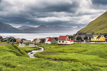 Colorful houses of Gjogv village and a small river flows into fjord. Faroe Islands, Denmark - obrazy, fototapety, plakaty