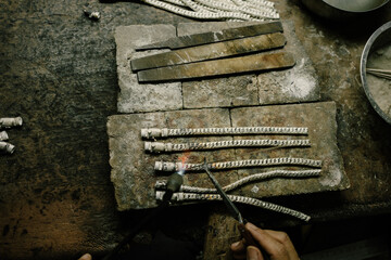 Jeweler at work in jewelry. Desktop for craft jewelry making with professional tools. Close up view of tools. Silver jewelry. Unique local artwork in Nan Province northern thailand