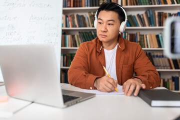 Japanese Male Taking Notes Looking At Laptop Learning Online Indoor