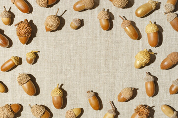 Autumn frame from natural dry acorns oak tree on linen fabric table, neutral background. Round border from natural materials. Autumn, fall concept. Minimal trend flat lay, top view, copy space