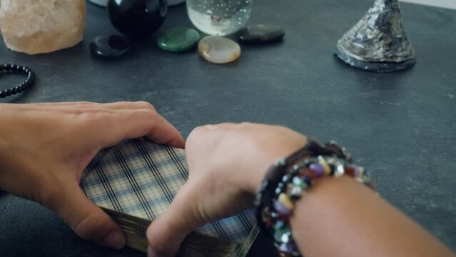 women's hands shuffle a deck of tarot cards