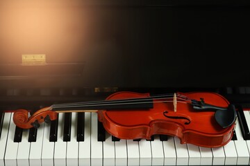 violin placed on a piano on a black background