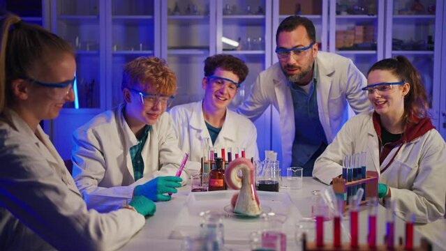 Excited science students with teacher doing chemical experiment in the laboratory at university.