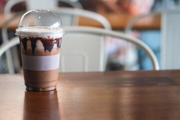 Iced mocha coffee with condensed milk and chocolate sauce in a plastic glass.