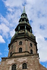 Fototapeta na wymiar Tower of St Peter church in Riga, Latvia, majestic vertical on blue sky and white clouds