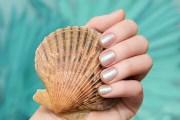 Female hand with vacation nail design. Glitter pearl nail polish manicure. Hand with pearl manicure...