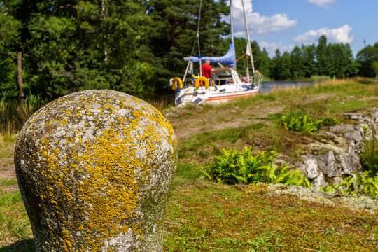 Old stone bollar at a canal with a sailboat