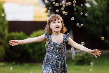 Little girl child enjoying playing with soap bubbles outdoors on summer day. Cute kid child catches soap bubbles in nature. happy childhood concept