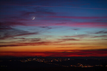 Crescent young Moon and planets on colorful sky.