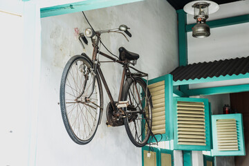Old retro bicycle hanging on the wall beside vintage windows.
