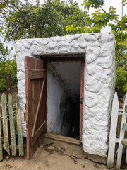 Open door historic vintage root cellar dug underground in the countryside near the trees.