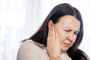 Young woman have a headache migraine stress or tinnitus - noise whistling in her ears