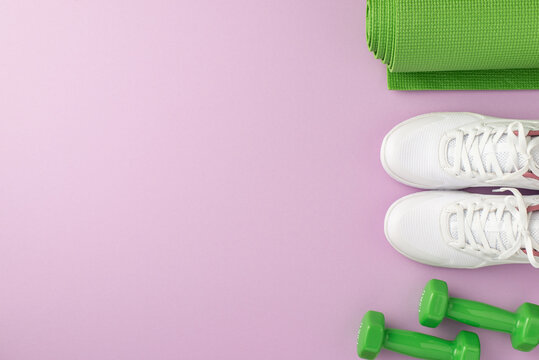 Active living concept. Top view photo of green sports mat dumbbells and white sneakers on isolated pastel violet background with empty space