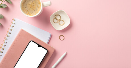 Business concept. Top panoramic view photo of workspace smartphone on pink organizers pen gold rings cup of coffee and eucalyptus on isolated pink background with copyspace