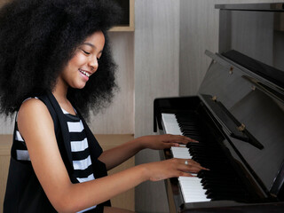 Young pretty beautiful American African girl playing piano.
