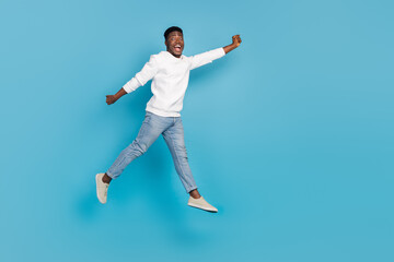 Fototapeta na wymiar Full length photo of astonished satisfied person jump fly raise hand isolated on blue color background