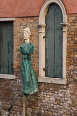 Fototapeta na wymiar visual effect - woman face sculpture on a wall and plastic bag that looks as if she's wearing dress - the green bag is not so close to the wall but seems like it is. 