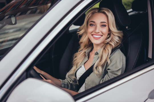 Photo of positive gorgeous lady sitting car front seat hold wheel look through window