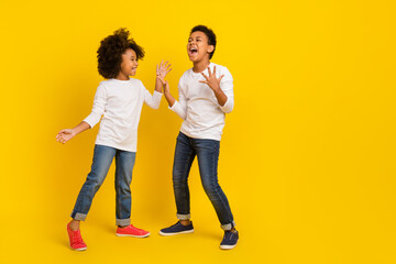 Photo of attractive impressed schoolkids dressed white shirts screaming empty space isolated yellow...